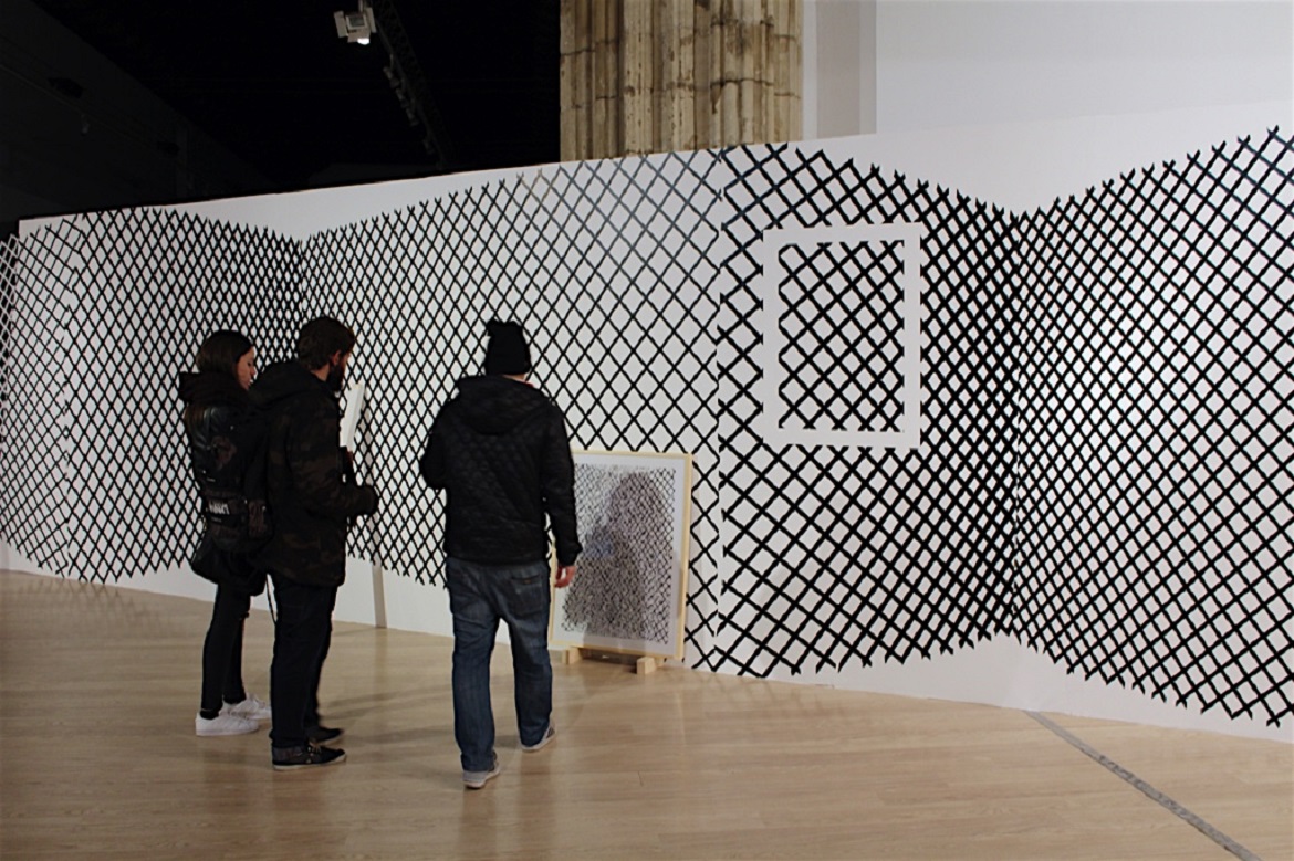 Tres personas observando una obra gráfica en una exposición