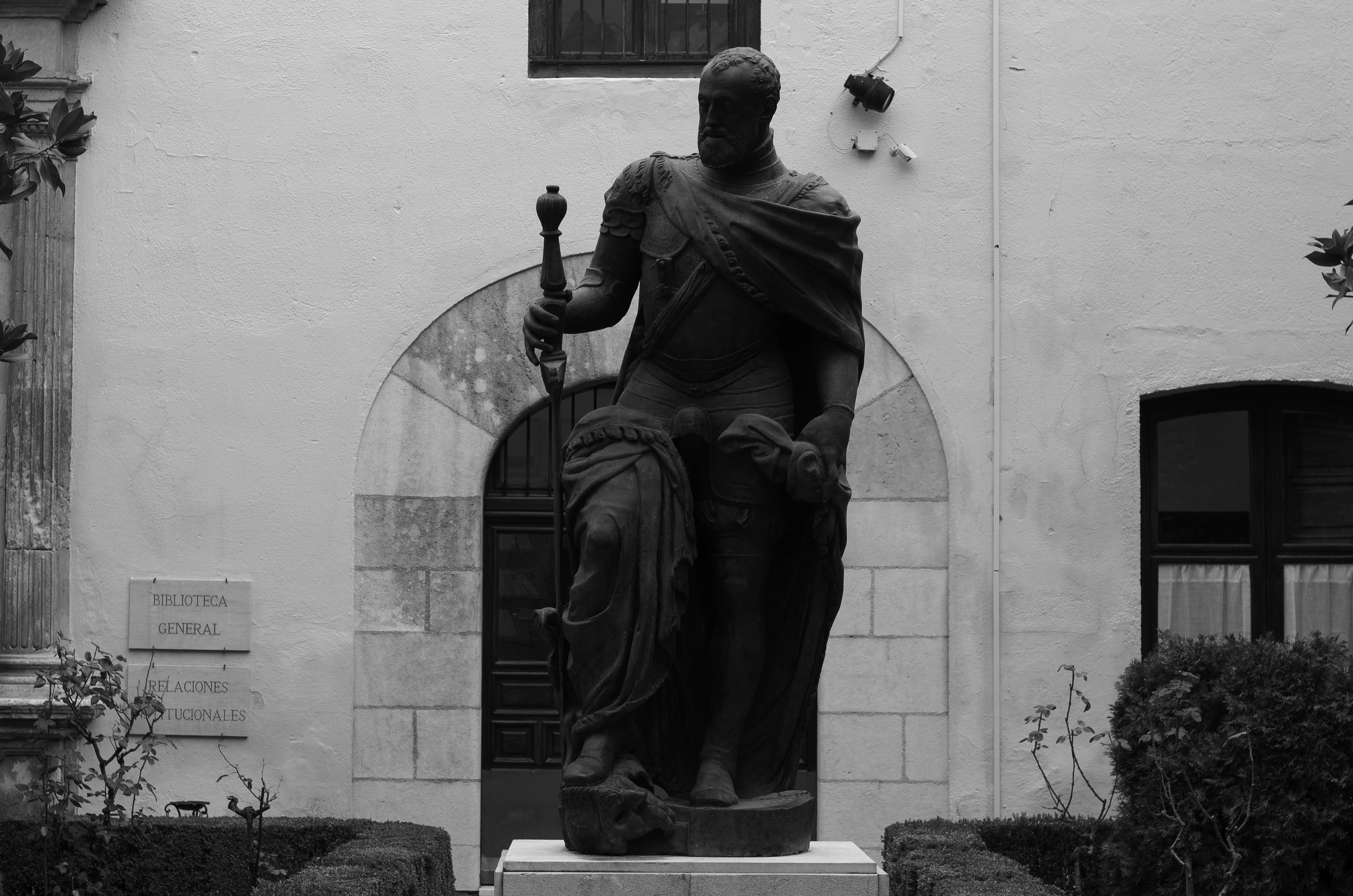 Fotografía en blanco y negro de la estatua de Carlos V ubicada en el Patio del Archivo del Hospital Real de Granada
