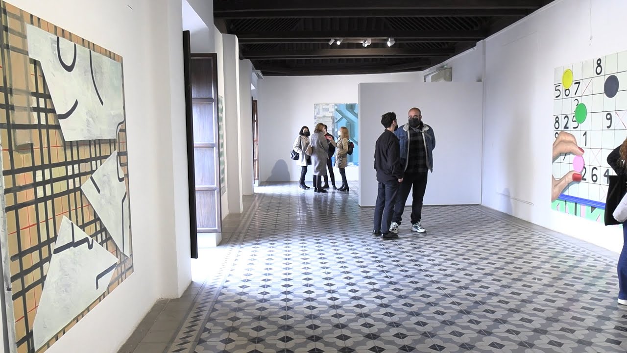 Dos personas viendo obras de arte en una sala de exposiciones