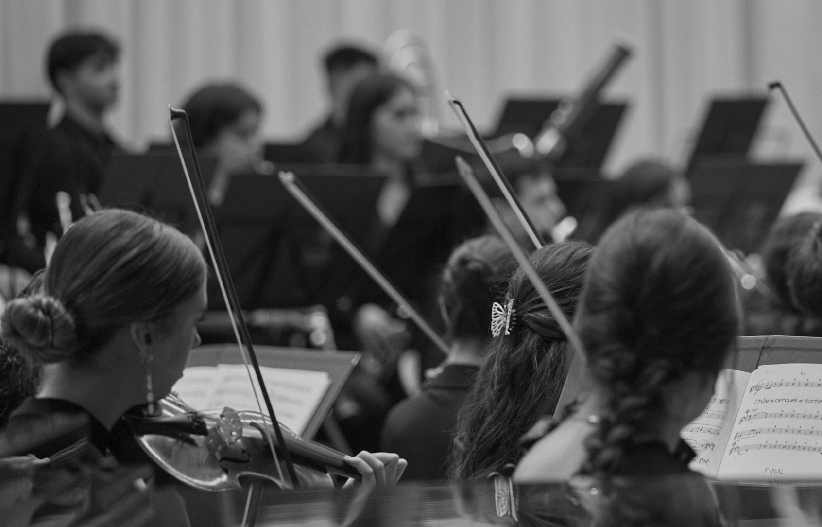 Fotografía en blanco y negro de la sección de violines de la Orquesta de la UGR