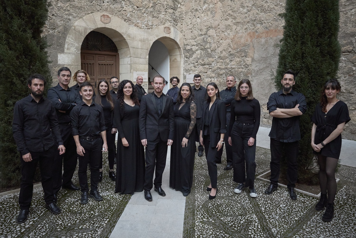 Fotografía de los integrantes del Coro de la UGR posando de pie en un patio del Hospital Real de Granada