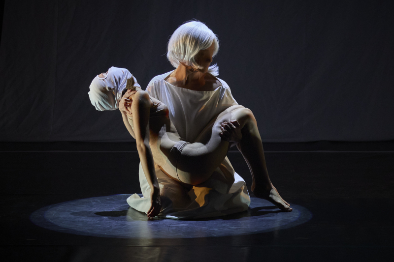 FITUG 2025 Escena de una representación teatral en la que aparece una persona de rodillas sujetando a otra en brazos