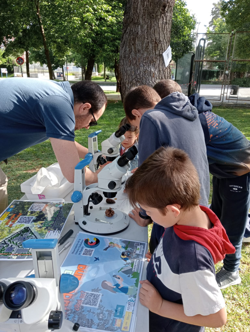 Semana de la ciencia UGR 2024 Fotografía de unos cuantos niños jugando con un microscopio
